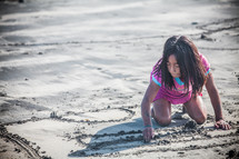 girl child drawing in the sand 