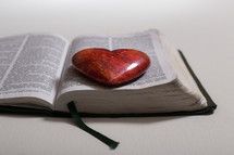 red heart shaped stone on the pages of a Bible 