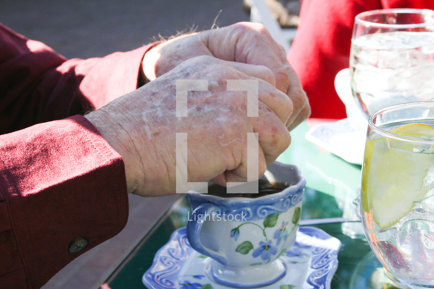 an elderly man putting sugar in tea 