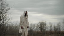 Jesus Christ after the easter Sunday resurrection or bible nomad, Christian prophet, monk or religious man in white tunic and sandals walking in the Jerusalem wilderness in cinematic slow motion.