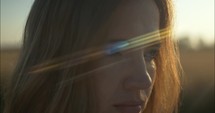 Sunlight light leaks on woman's face in summer sunset.