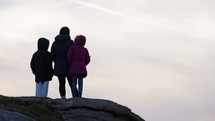 Young Family Outdoors Together Backlit On Rocks