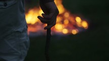 Young Man Throws Stick into a Bonfire