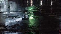 Drizzle, puddles and night urban lights reflecting on the road