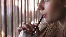 Girl drinking something out of a straw. 