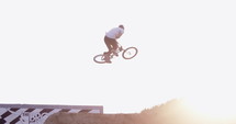 Extreme BMX rider does down whip table trick over dirt jump