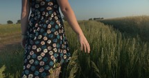 Woman in flower dress touching grass walking in slow motion.