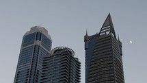 Moon behind buildings in city of Dubai.