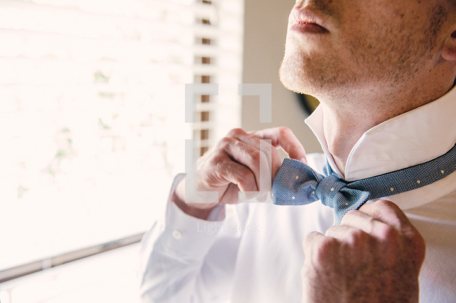 groom adjusting his bow tie 