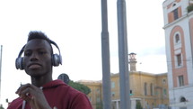 young man walking down the street listing to headphones 