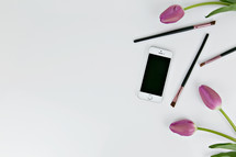 iPhone, makeup brushes, and pink tulips 