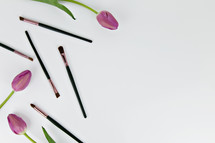 pink tulips and paint brushes on a white background 