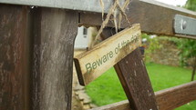 Beware of the dog sign hanging on a wood gate.