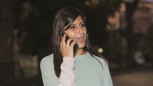 a young woman talking on a cellphone at night 