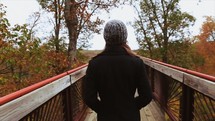 a woman walking on a wood deck looking at fall colors 