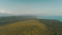 Cinematic aerial view over green landscape and blue Caribbean sea in Costa Rica during summer	