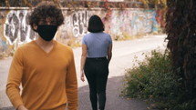 two people walking past each other wearing masks