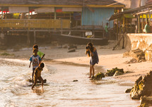 a woman photographing kids playing in the sea waves in Luwuk