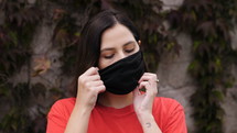 a woman putting on a face mask 