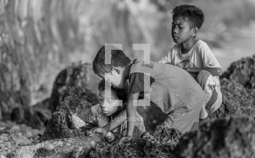 children exploring rocks along a shore in Luwuk