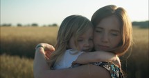 Happy mother and daughter hugging in sunset.