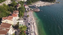 Aerial: Kotor beach in Montenegro with bustling shoreline and town