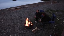 Warming By Campfire At Lake In Mountains