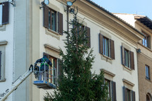 Florence, Italy - December 03, 2023: Christmas tree installation in the central square of Florence. Workers on lifting platforms mount the Christmas lights.