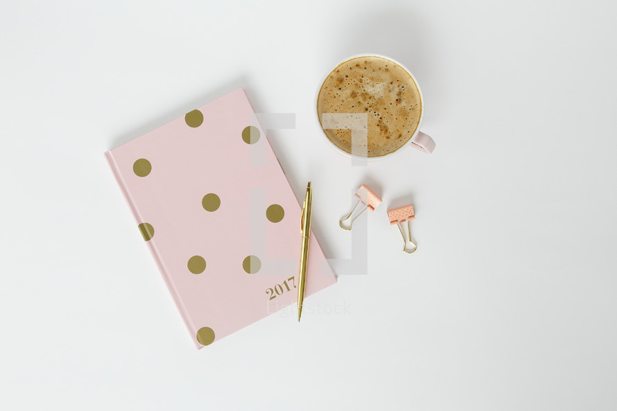 latte, pen, polka dot planner, and clips on a desk 