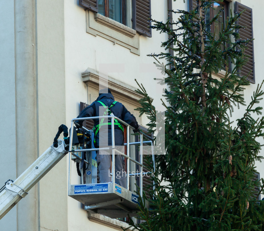 Florence, Italy - December 03, 2023: Christmas tree installation in the central square of Florence. Workers on lifting platforms mount the Christmas lights.