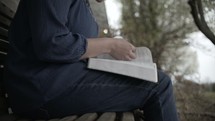 a person sitting on a bench reading a Bible 