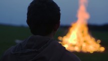 Young Man sits in Front of a Bonfire