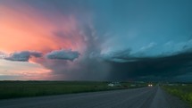 Lone Car Passes On A Quiet Road With A Beautiful Storm At Sunset