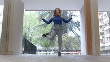 Woman dancing in an outdoor hallway.