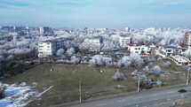 Fly Over Buildings With Snow-Covered Trees In The City Of Galati, Romania. Aerial Drone Shot	