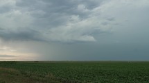 Distant lightning flashes in thunderstorm. Dark storm clouds move across prairie and farmland in rural America with lightning bolt strike and distant highway.