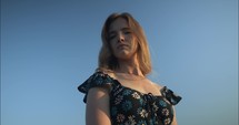 Portrait of young woman in flower dress looking at camera.