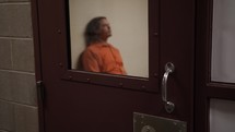 Sad, depressed criminal. Man locked up behind prison bars in his prison cell for criminal activity in cinematic slow motion.
