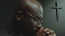 Close-Up of Black Clergyman Praying to God with Eyes Closed