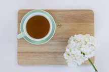 wood citing board with flowers, and cup of tea 