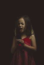 little girl singing into cellphone with feeling