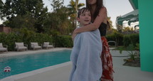 Mother hugging son in towel after swimming in outdoor pool