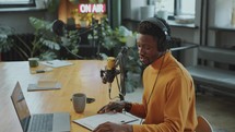 Journalist Reading Notes on Paper and Laptop as Recording Audio Podcast
