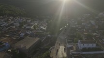 Drone flies along river in mountain town into sunset