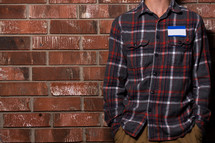 man in a plaid shirt with a blank name tag 