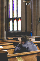 Man kneeling and praying in church.