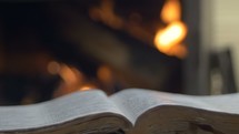 open Bible in front of a fire 
