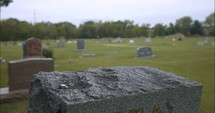 Graveyard tombstone grave in cemetery on cloudy day.