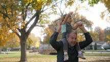 grandfather with his granddaughter playing in fall leaves 