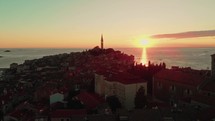 drone flies over medieval town with church at sunset